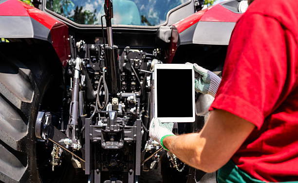 Agricultural machinery mechanic uses digital tablet to diagnose tractor.